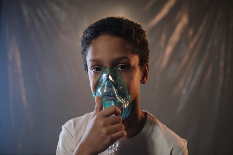 Breathing Emergencies Portrait of a child using an oxygen mask indoors, highlighting health care needs.